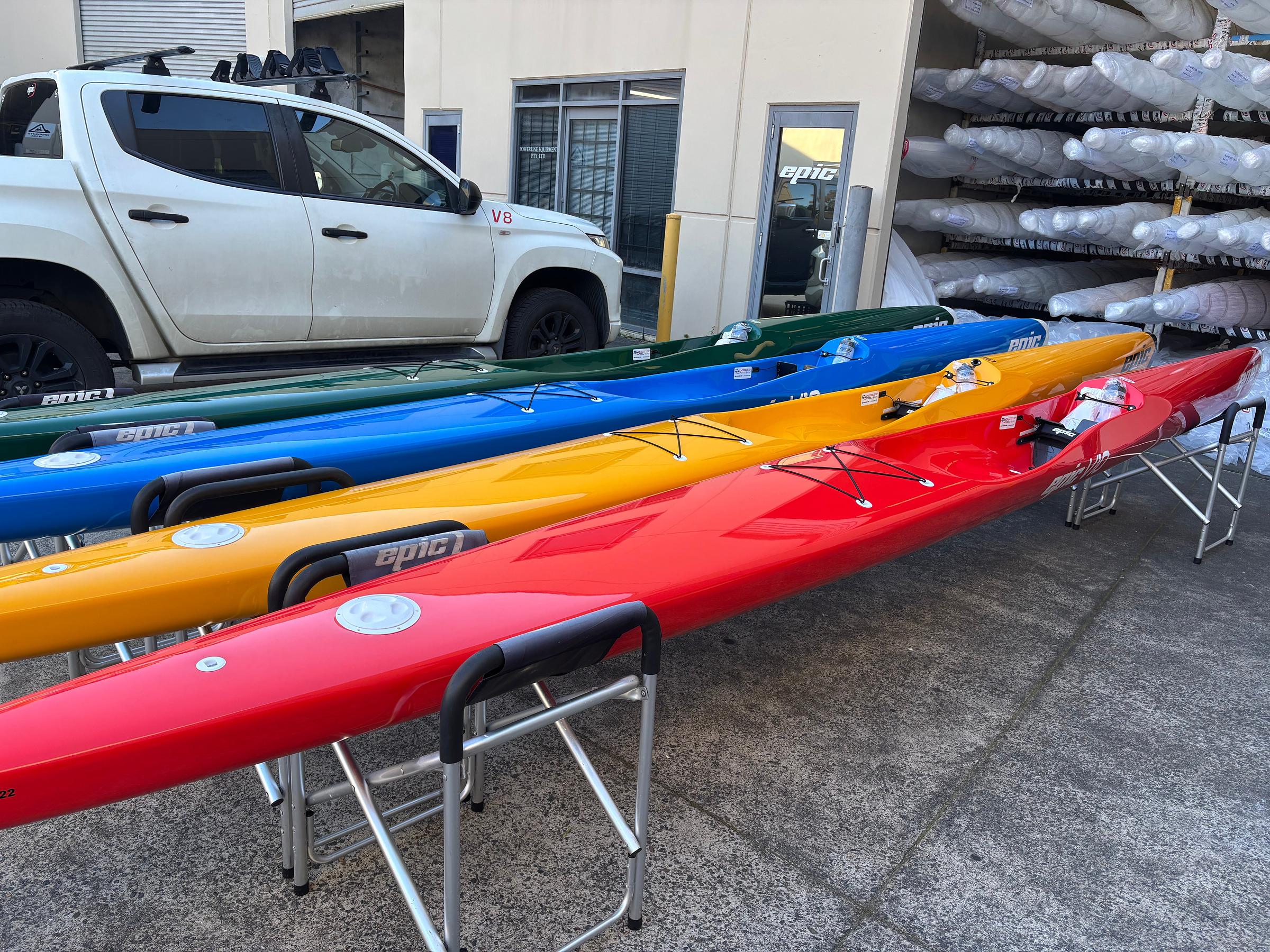 Epic surfskis in red, yellow, blue and green on boat stands